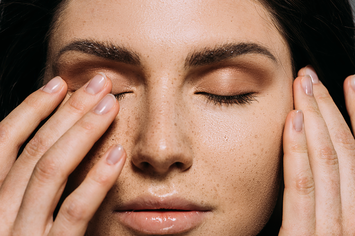 Close up view of tender girl with freckles on face touching closed eyes