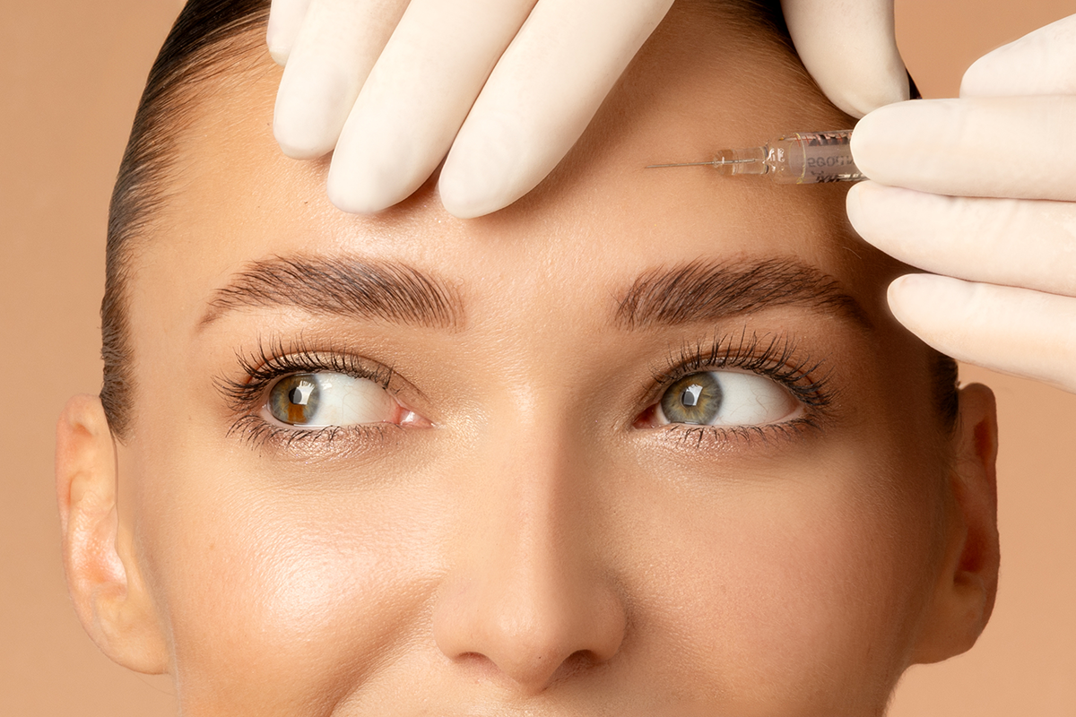 Closeup shot of young Caucasian woman getting beauty cosmetic injection in forehead