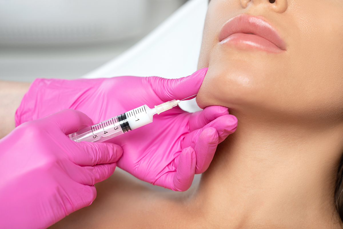 Cosmetologist makes lipolytic injections to burn fat on the chin, cheeks and neck of a woman