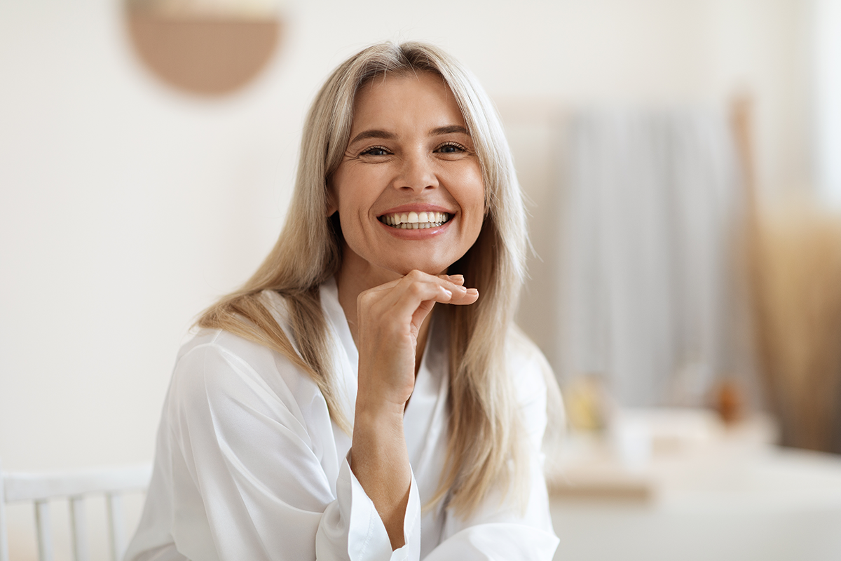 Happy blonde woman posing at white bathroom at home