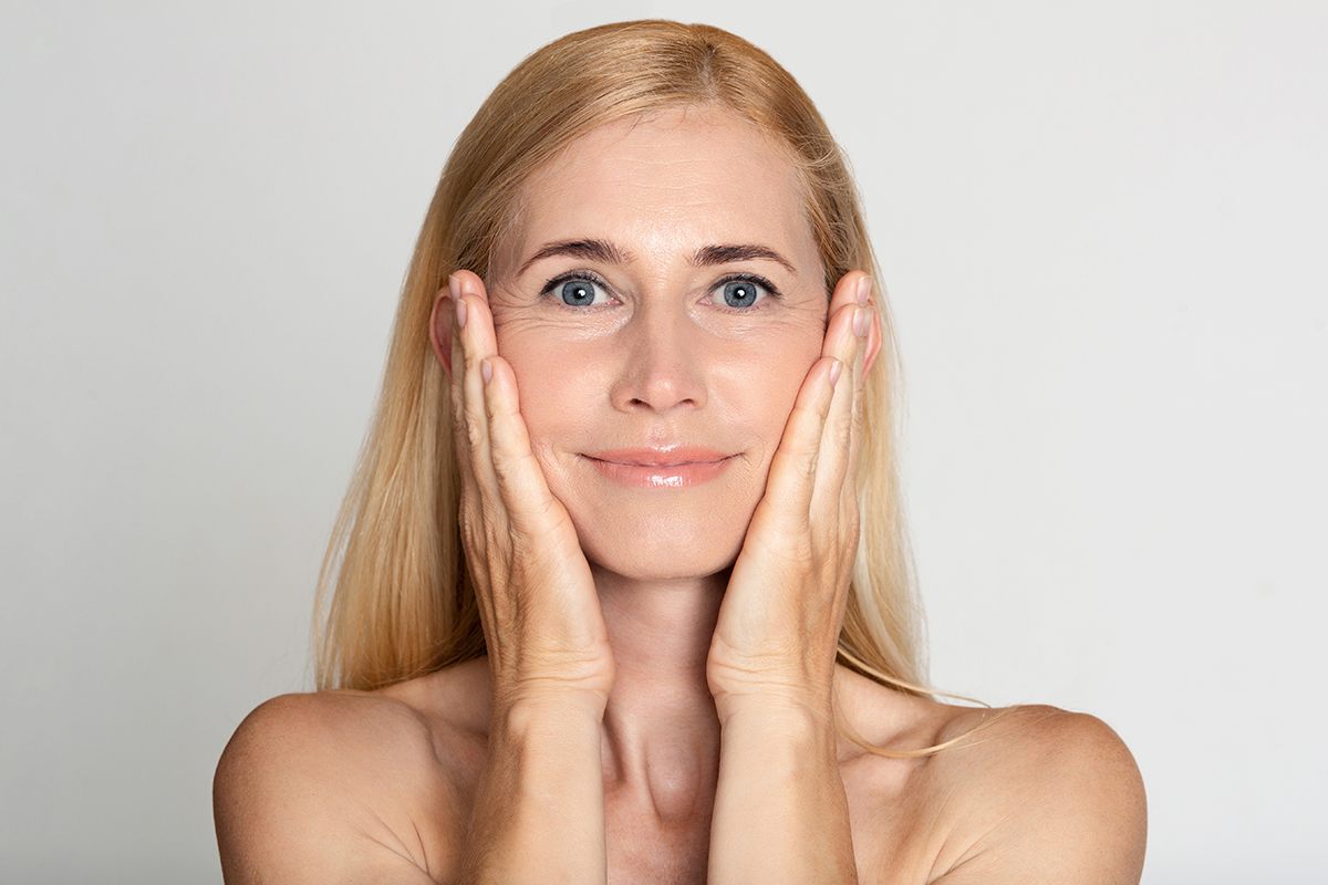 Middle-aged woman touching cheeks Middle-aged woman touching cheeks