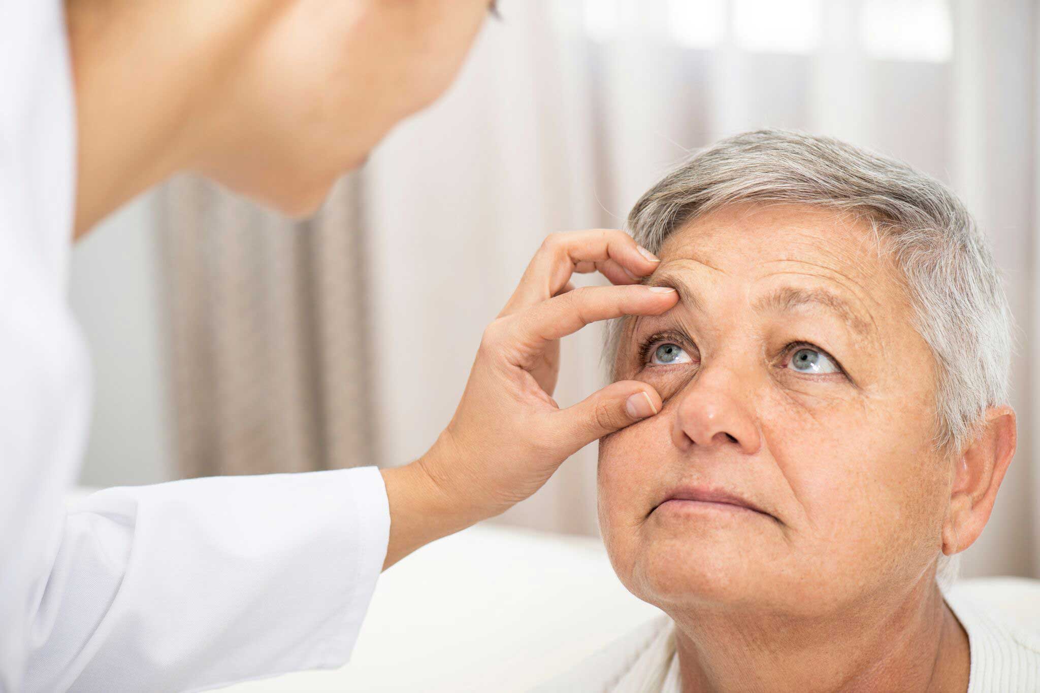 senior patient getting eye looked at by doctor senior patient getting eye looked at by doctor