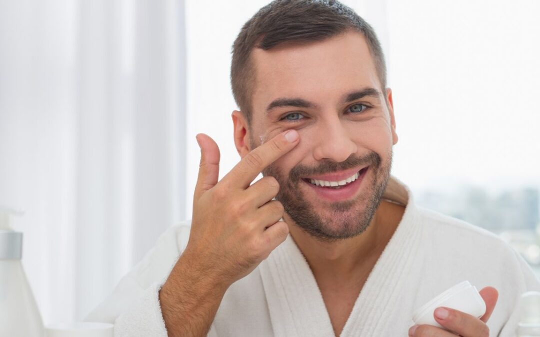 cheerful man smiling while applying facial cream